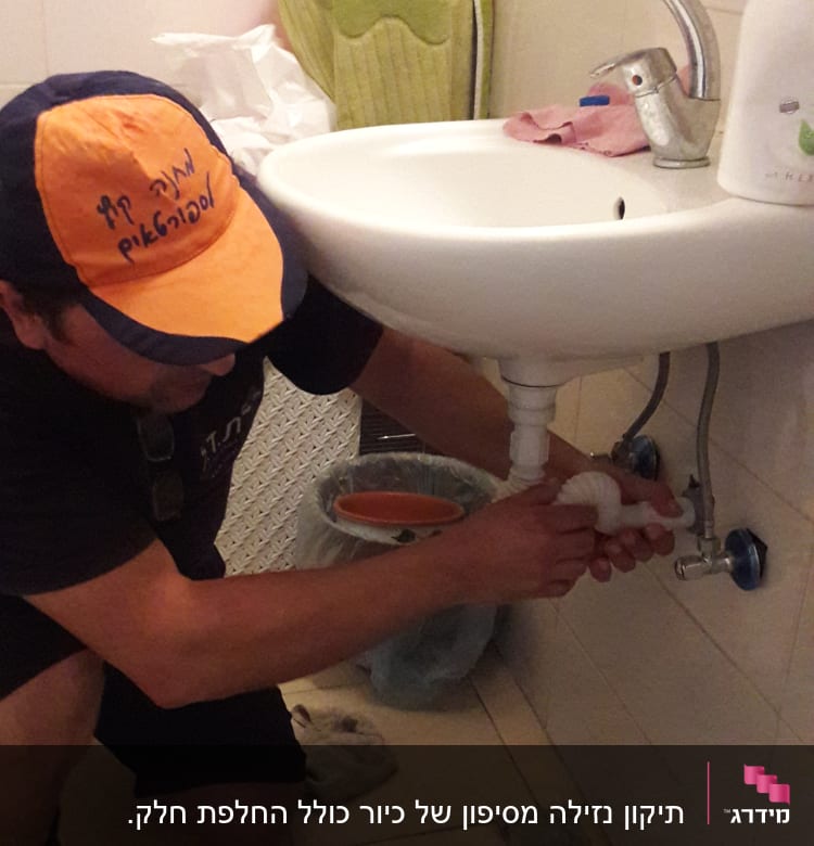 אינסטלטור מתקן צינור מתחת לכיור בחדר אמבטיה